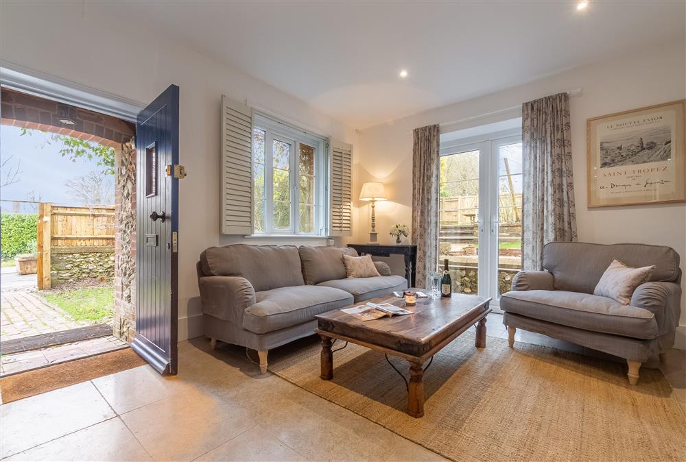 Open-plan sitting room with comfortable sofas and french doors to the garden at 1 Church Cottages, Westmeston