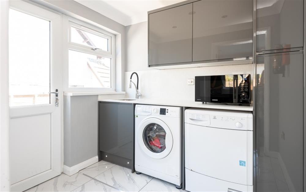 The utility room with washer, dryer and microwave at 1 Crestfields in Strete