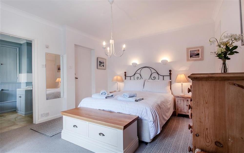 The master bedroom with TV, balcony and en suite bathroom at 1 Kings Cottages in Salcombe