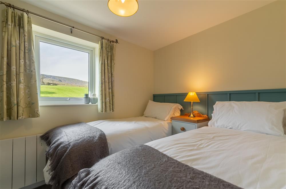 Bedroom two with twin single beds and river views at 1 Riverside Cottage, Burnsall