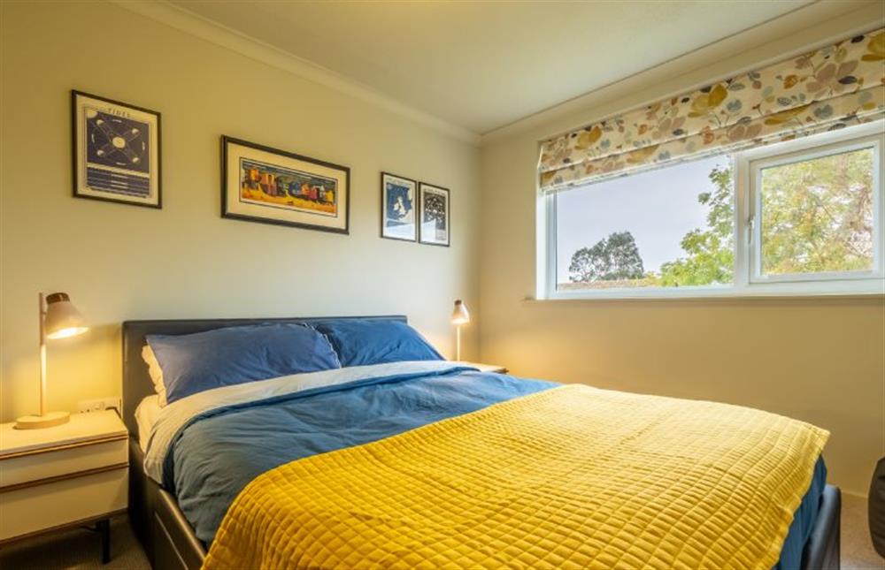First floor: Master bedroom with colourful artworks at 12 The Close, Brancaster Staithe near Kings Lynn