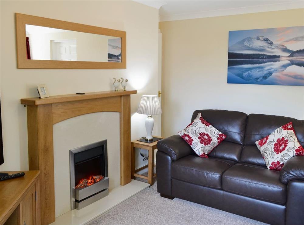 Attractive living and dining room with feature fireplace at 2 Lonsdale House in Keswick, Angus
