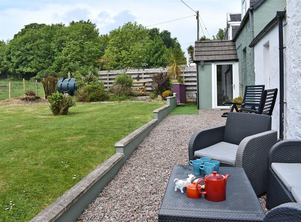 Enclosed lawned garden with courtyard, patio and garden furniture at 2 Northbank Cottages in Whiting Bay, Isle of Arran, Scotland