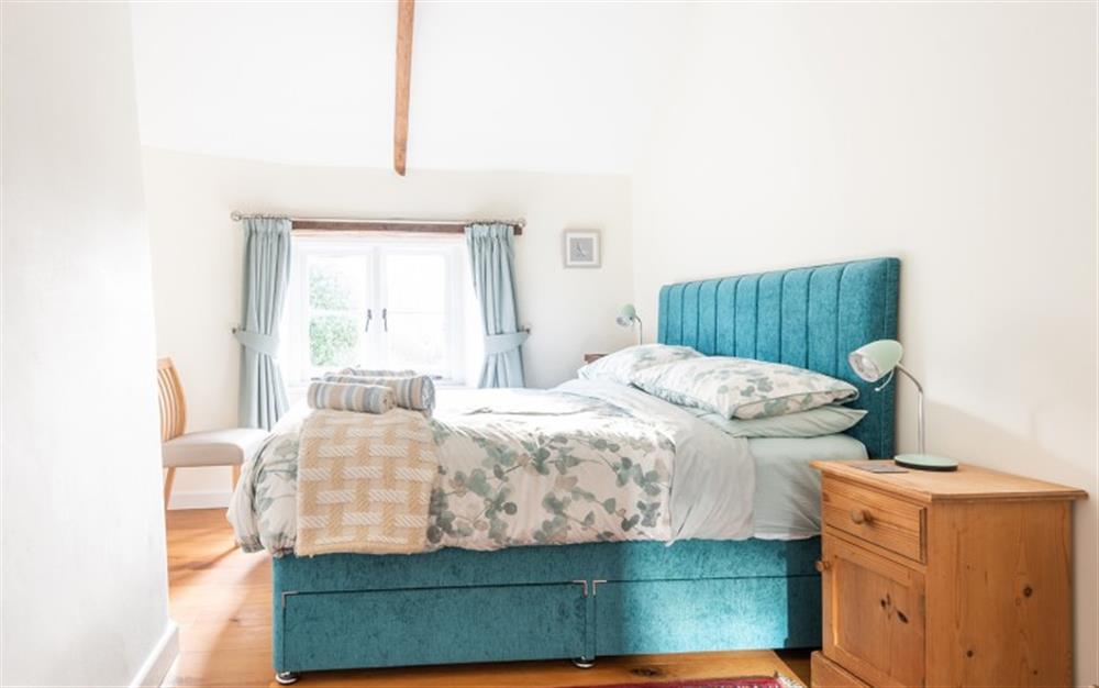 The master bedroom with a king size bed and views over the garden at 2 Rose Cottages in Sherford