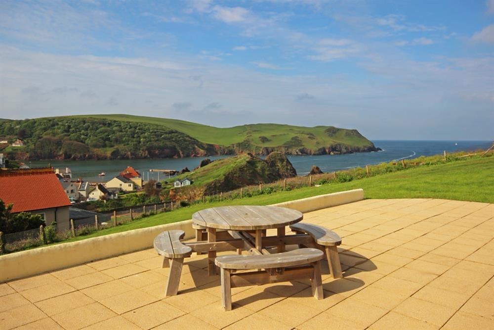Large South-facing terrace with garden chairs and small table at 2 Sea Gardens in Hope Cove, Nr Kingsbridge