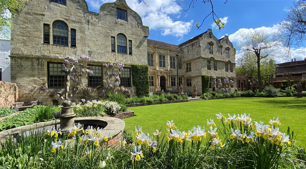 View of a historic stone house across a garden with statues at 20 Ogleforth in York, North Yorkshire