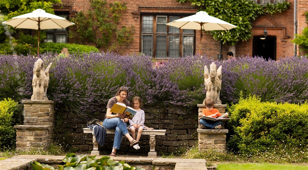 Woman and two children sat reading near garden ornaments with lavender and umbrellas behind them at 20 Ogleforth in York, North Yorkshire