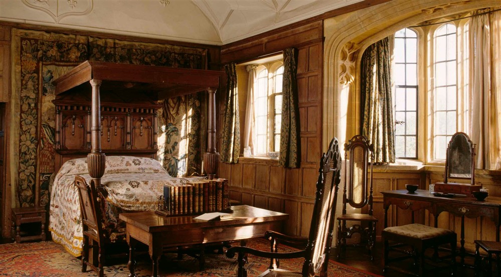 View of Great Chamber with large oak bed with panelled tester and large curved windows at 3 Lytes Cottage in Somerton, Somerset