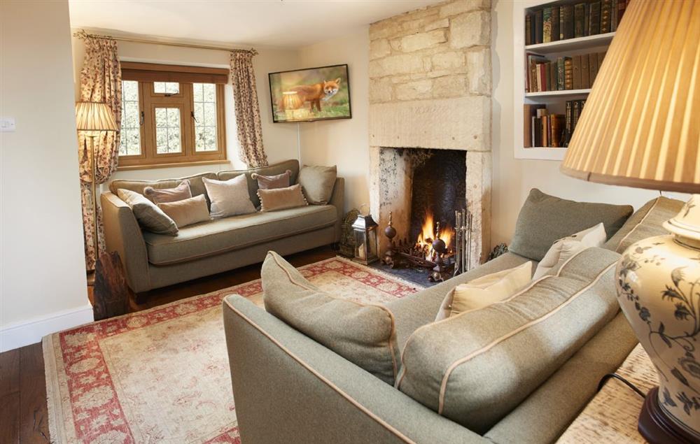 Sitting room with Cotswold stone fireplace and roaring open fire