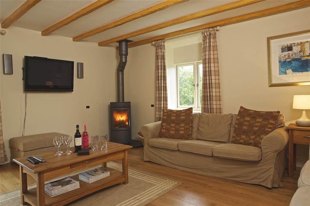 A spacious living room has double sofas and wood-burning stove at 4 Bolberry Court in Bolberry, Hope Cove