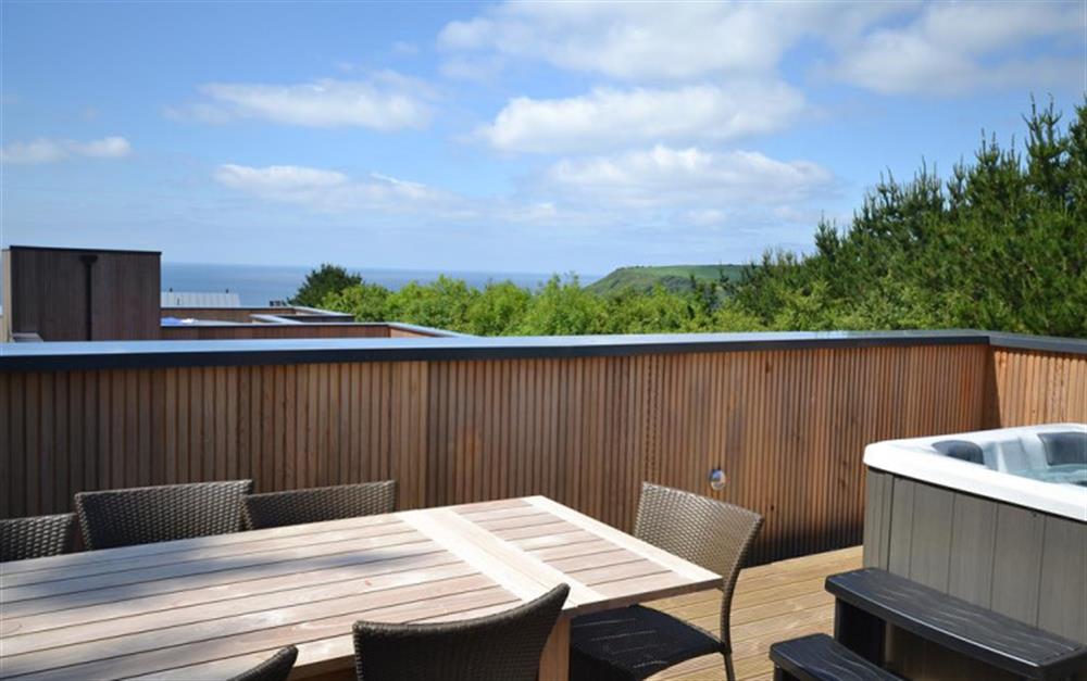 The front roof terrace with hot tub, patio table, chairs and barbecue and views over the sea. at 47 Talland in Looe