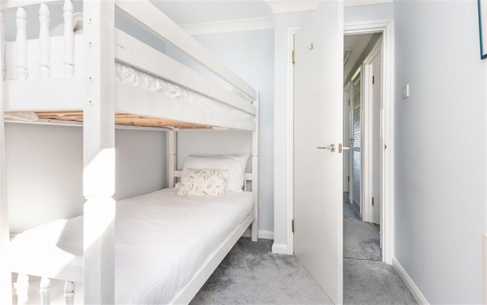 The white furniture in the bunk room is fresh and bright against the blue walls.