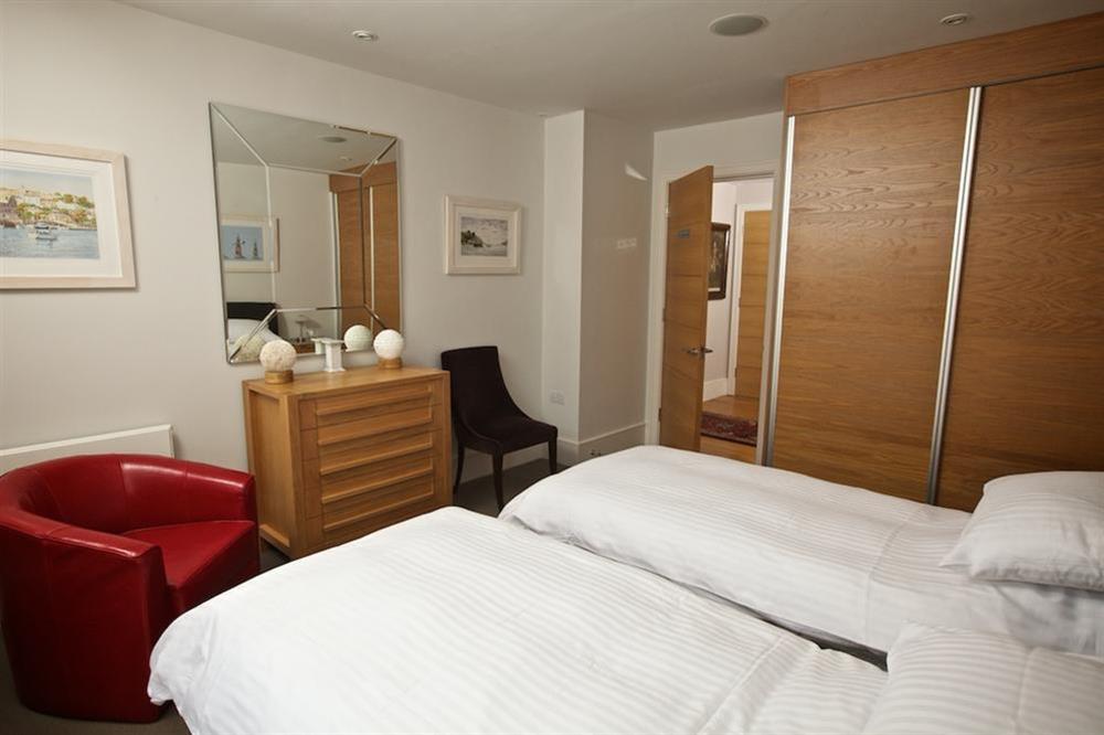 Twin bedroom with leather framed beds and red leather bucket chair at 7 Dart Marina in Sandquay Road, Dartmouth