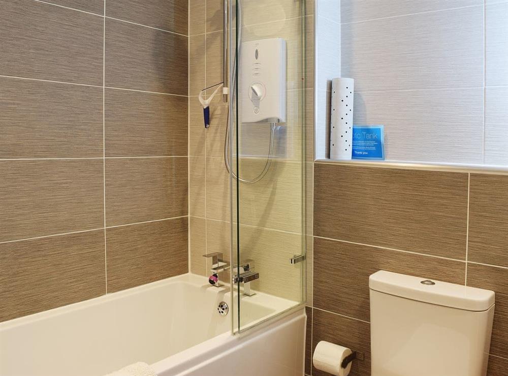 The fully tiled, modern bathroom has a shower of the bath at 7 Ladstock Hall (deluxe) in Keswick, Cumbria