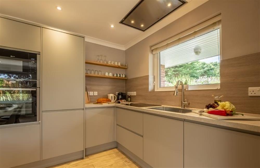Open-plan kitchen/dining area with electric oven and hob, microwave, dishwasher, fridge-freezer, washing machine and dining table with seating for four guests and door leading to the enclosed garden