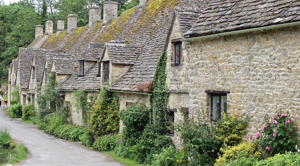 Row of stone gabled cottages with plants growing on the outside walls. at 9 Arlington Row in Cirencester, Gloucestershire