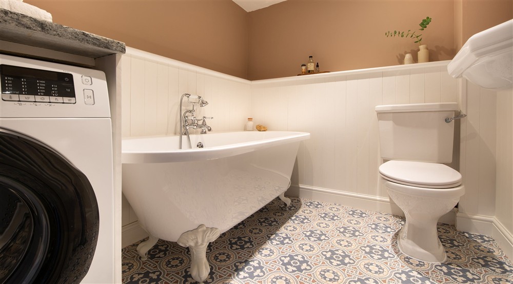 The twin bedroom's en-suite bathroom on the ground floor of Abermydyr, with roll-top bath with shower attachment and combined washing machine and tumble dryer, Ceredigion at Abermydyr in Aberaeron, Ceredigion