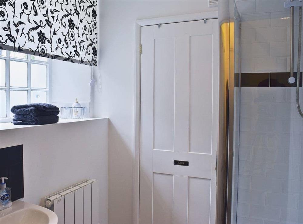 Shower room with WC, basin, shower and washer/dryer at Acorn Lodge Cottage in Keswick, Cumbria