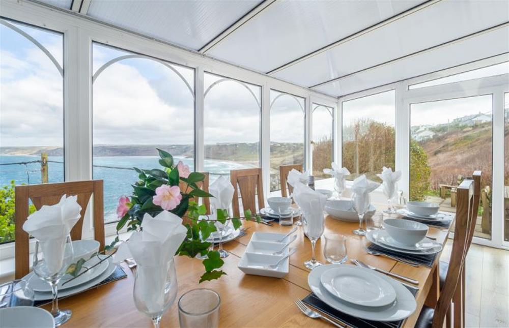Conservatory and dining room with a table and seating for eight,, overlooking the sea at Adanac, Sennen Cove