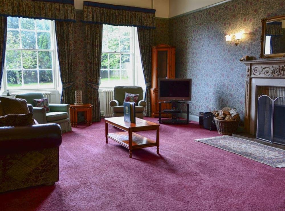 Large sitting room with open fire at Akeld Manor House in Akeld, Wooler, Northumberland., Great Britain