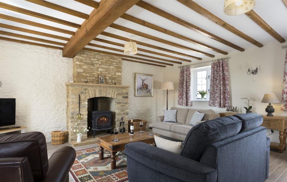 Sitting room with wood burning stove and exposed beams at Alysas Cottage, Chipping Norton