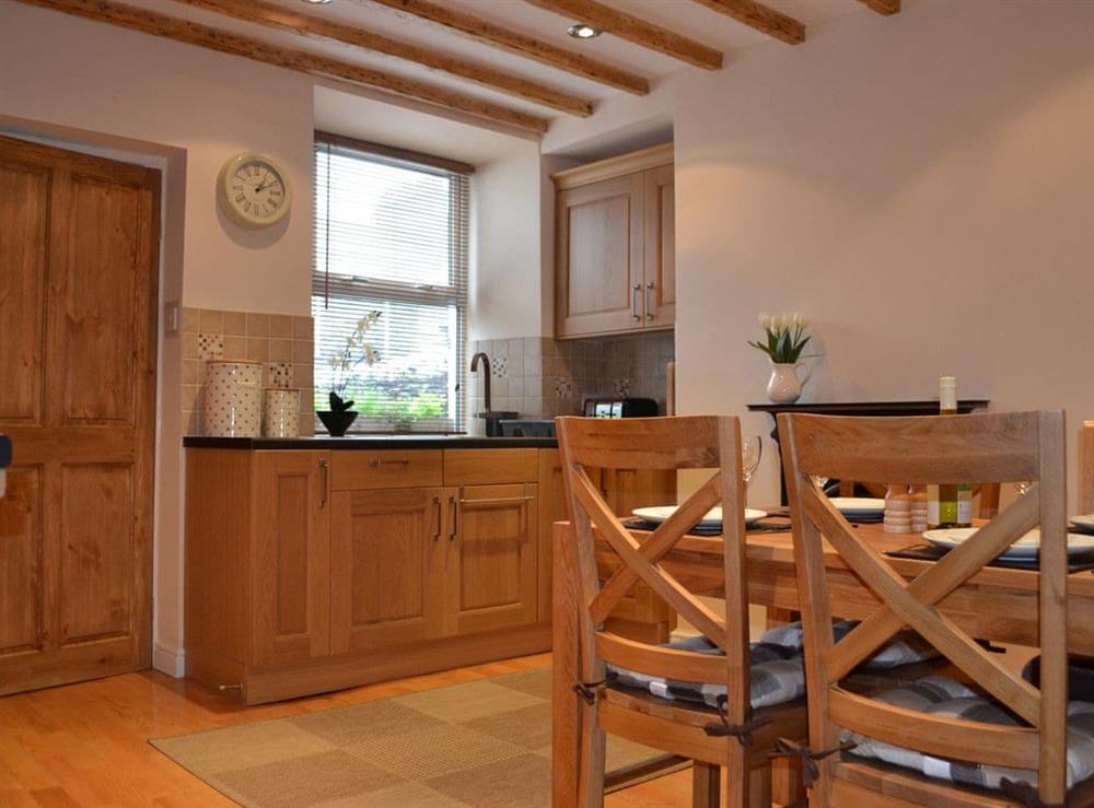 Kitchen/diner with wooden floor and exposed beams at Amberleigh House in Windermere, Cumbria