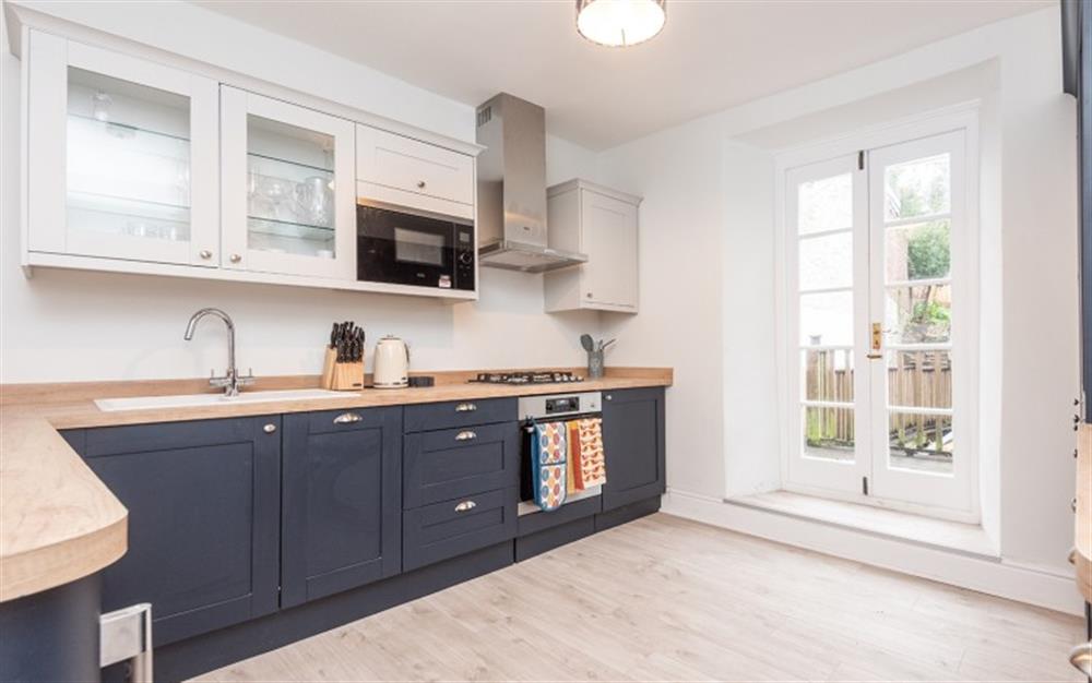 Fully-equipped kitchen with doors leading to rear garden and patio area at Anchorage in Dartmouth