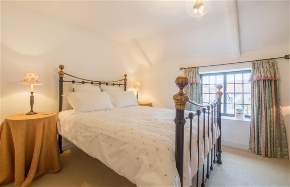 First floor: Master bedroom with king-size wrought iron bed at Angel Cottage, Great Walsingham