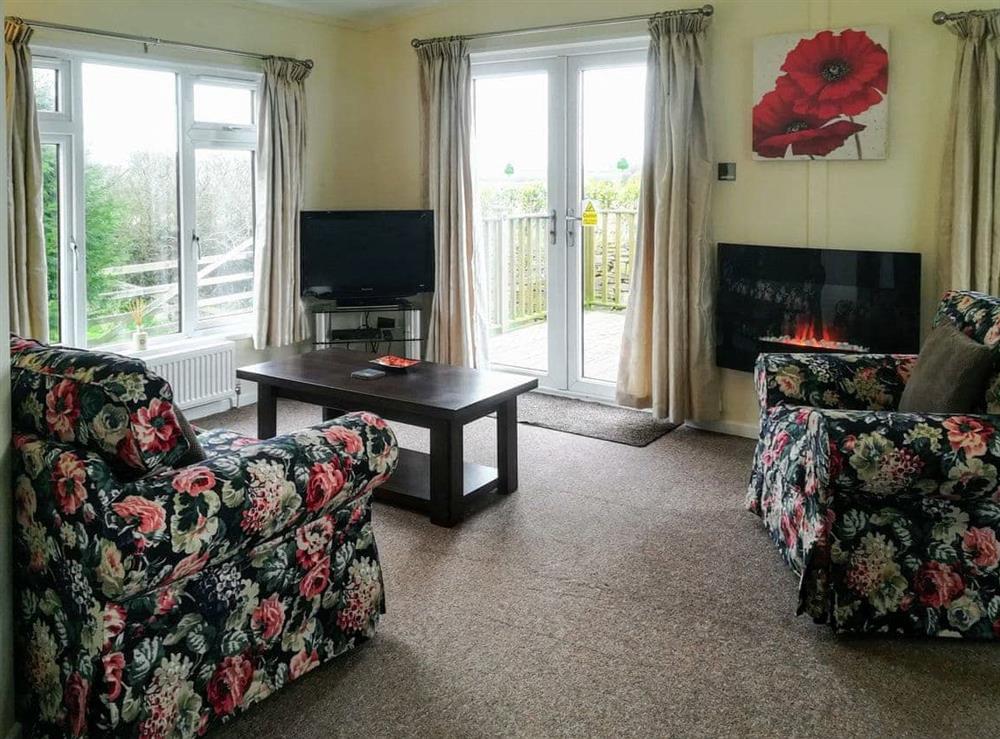 Welcoming living area with French doors to decked terrace at Apple Blossom Cottage in St Ervan, near Padstow, Cornwall