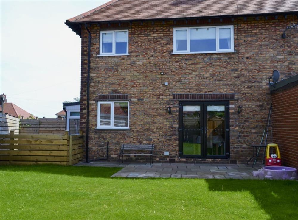 Enclosed lawned garden with patio and garden furniture at Apple Tree House in Scarborough, North Yorkshire