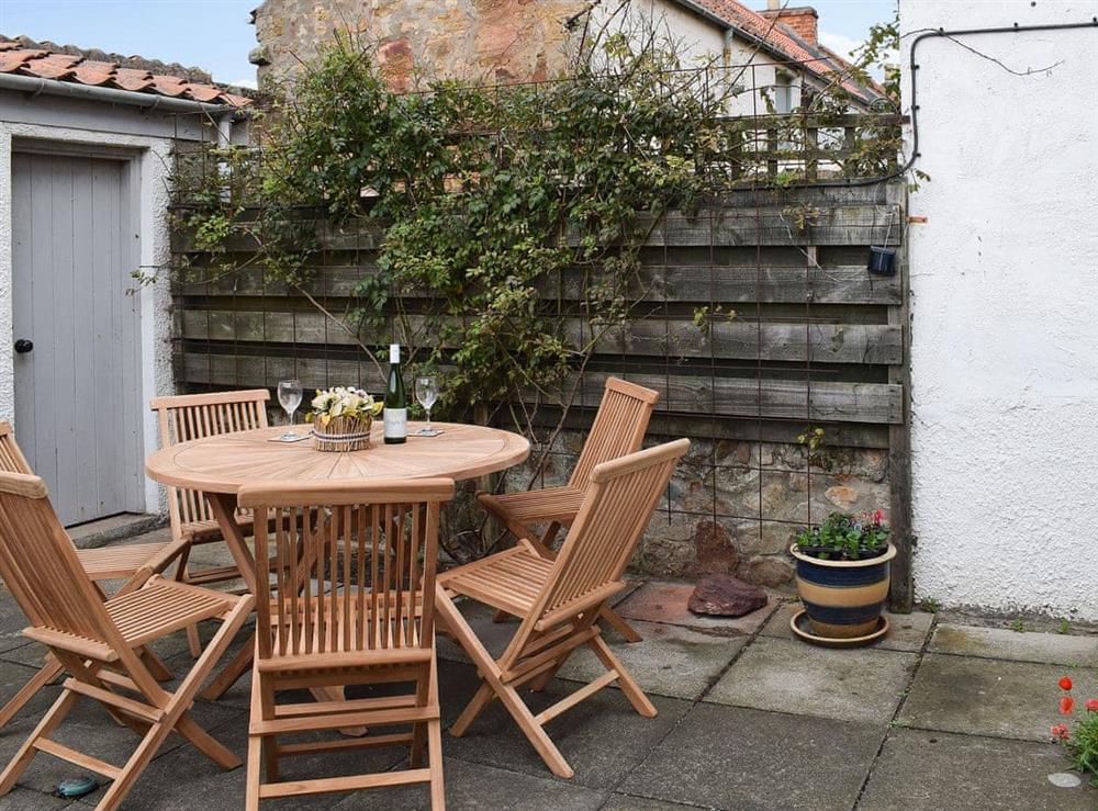 Modest flagged courtyard garden with table and chairs at Arc House in Cellardyke, near Anstruther, Fife