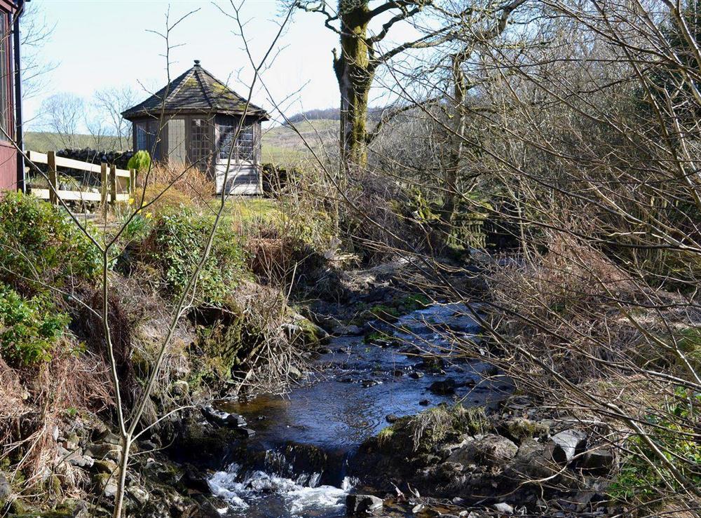 In addition to the summerhouse the cottage has a bridge over the adjacent stream min the garden at Arkland Mill in Crocketford, near Dumfries., Kirkcudbrightshire