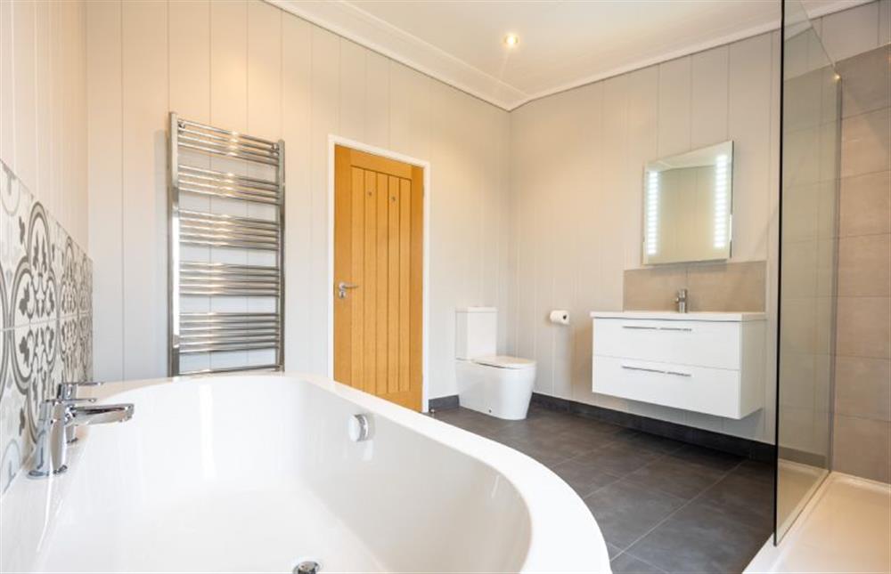 Ground floor: Bathroom with bath tub and shower at Avocet Lodge, Ingoldisthorpe near Kings Lynn