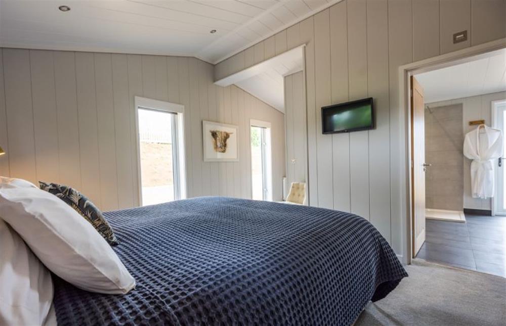 Ground floor: Super-king size bed and wall mounted television at Avocet Lodge, Ingoldisthorpe near Kings Lynn