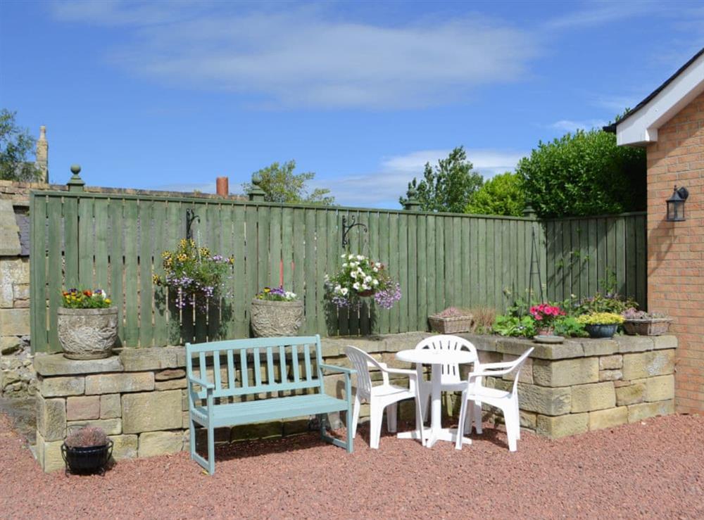 Gravelled patio with outdoor furniture at rear at Barkers Cottage in Ellington, near Druridge, Northumberland