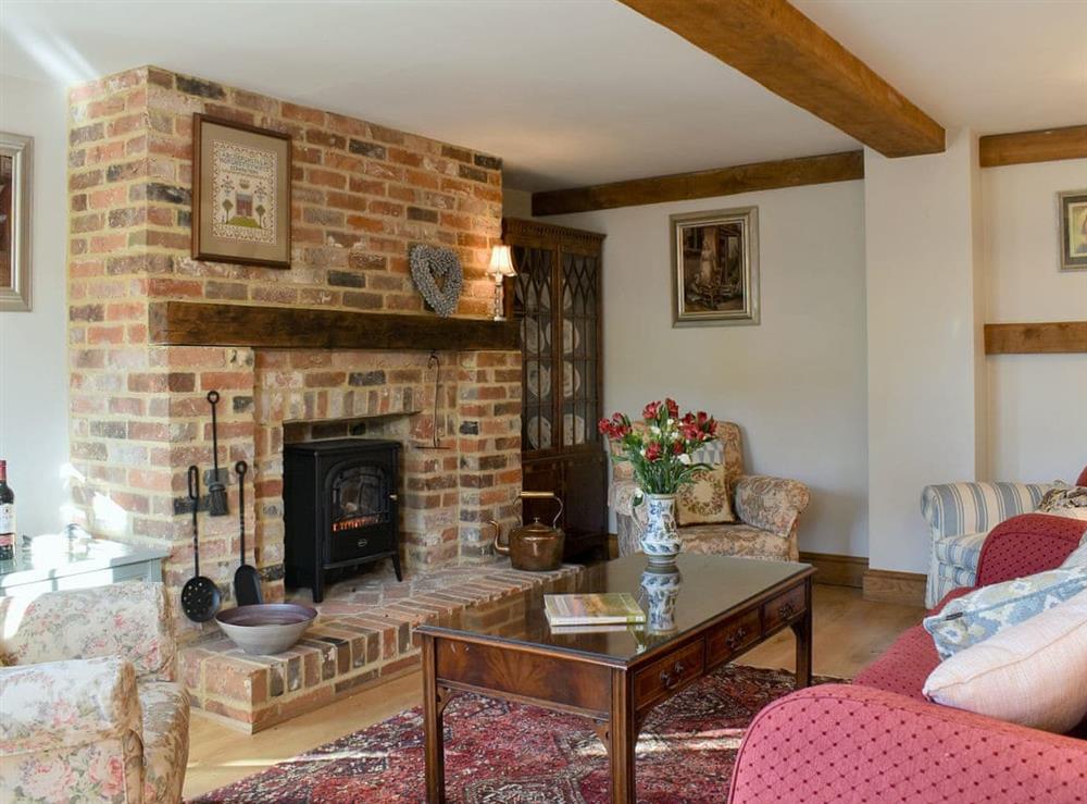 Living room with exposed brick fireplace housing a modern electric wood burner at Barn Cottage in Blackboys, near Uckfield, East Sussex