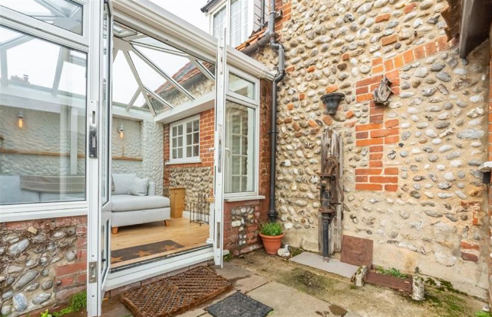 Ground floor: Sunny conservatory with corner sofa and double doors on to enclosed garden at Barn Cottage, Salthouse near Holt