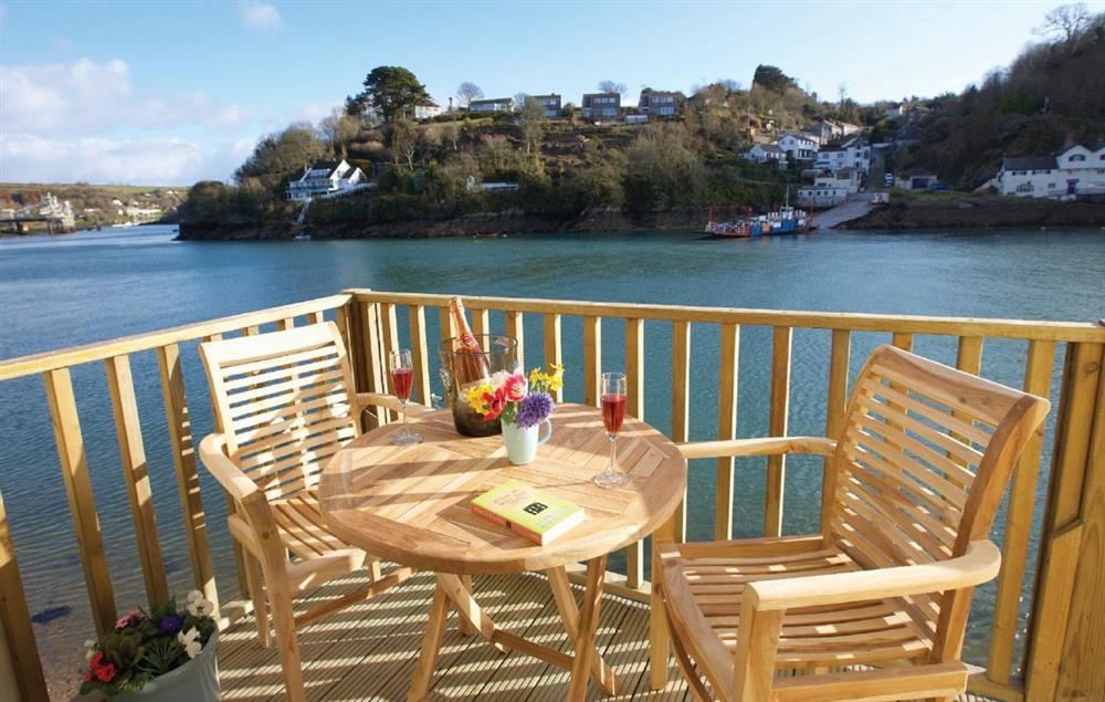 Decked balcony area with outdoor table and chairs, mooring and steps down to the water at Barnacles, Fowey