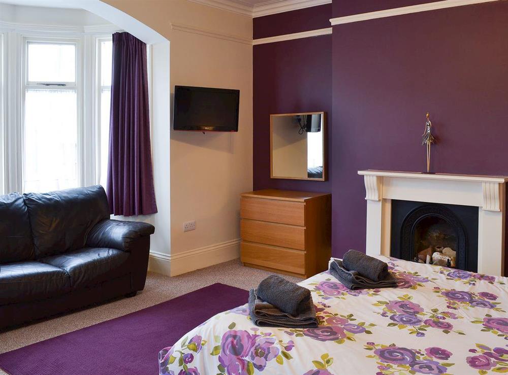 Double bedroom with comfy sofa and open fireplace at Bay House in Filey, North Yorkshire