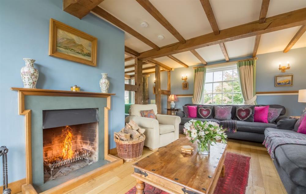 L-shaped sitting room with open log fire at Bearwood House, Pembridge