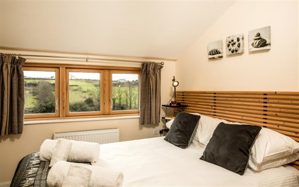 The bijou, second bedroom has a double bed and a chest of drawers. You can see the views across the fields and the edge of the golf course. at Birch Cottage in Falmouth