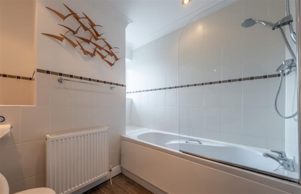 Bathroom with shower over the bath and a coastal theme at Birch Cottage, Northrepps near Cromer