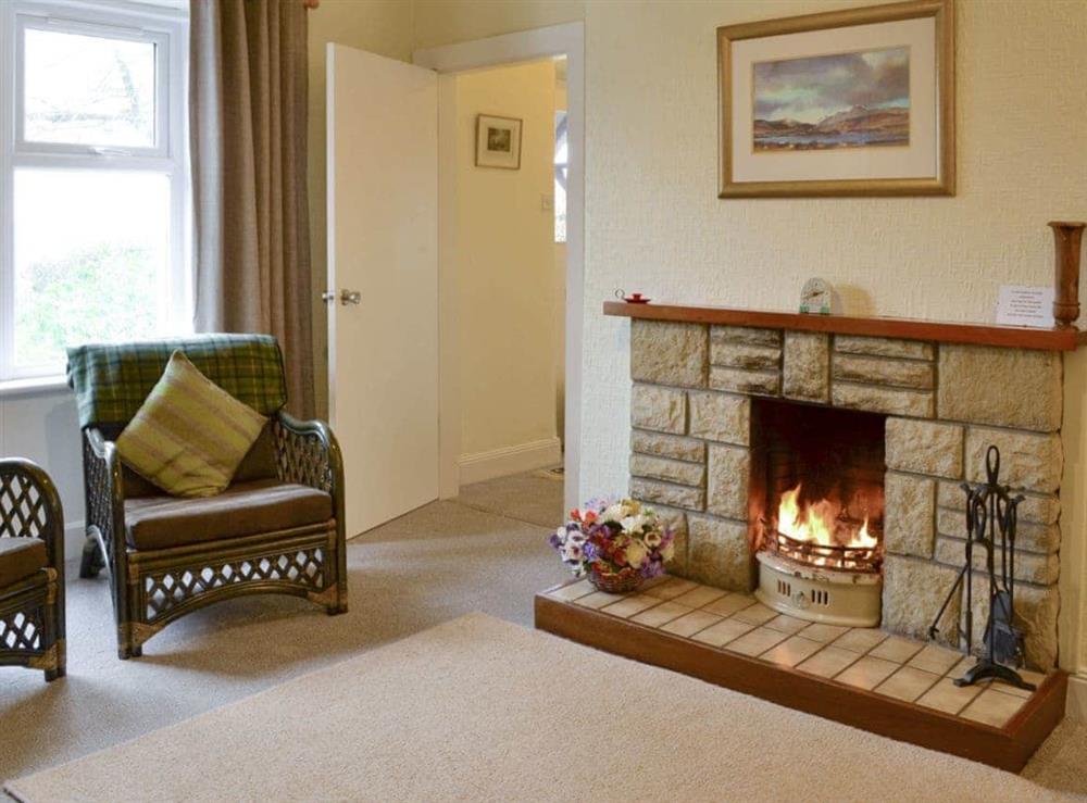 Welcoming open-fire within living room at Blairhosh Cottage in Balloch, Loch Lomond, Dumbartonshire