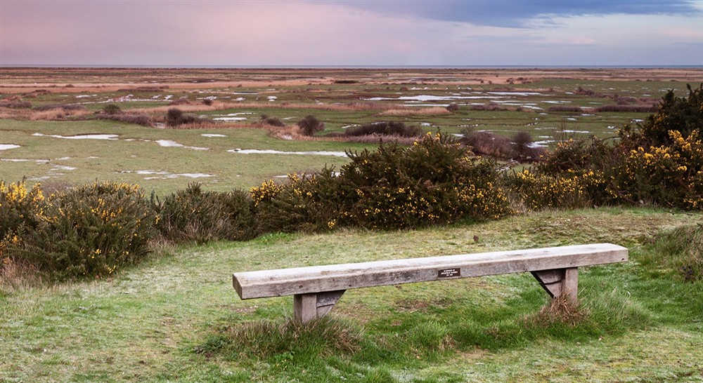 A bench with a view on Friary Hills overlooking Blakeney Freshes, Norfolk at Blakeney Lodge in Blakeney, Norfolk