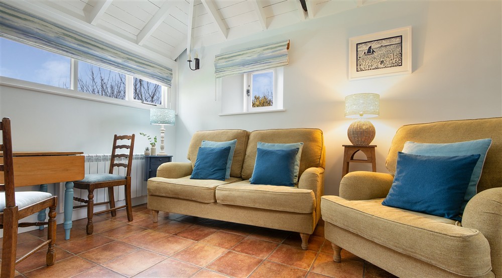 The seating area in the open-plan living space with a sofa and armchair at Blakeney Lodge in Blakeney, Norfolk