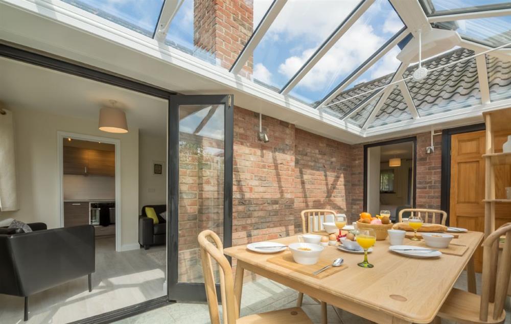Ground floor: Dining conservatory with doors leading to the garden at Bluebell Cottage, Hindringham, Fakenham