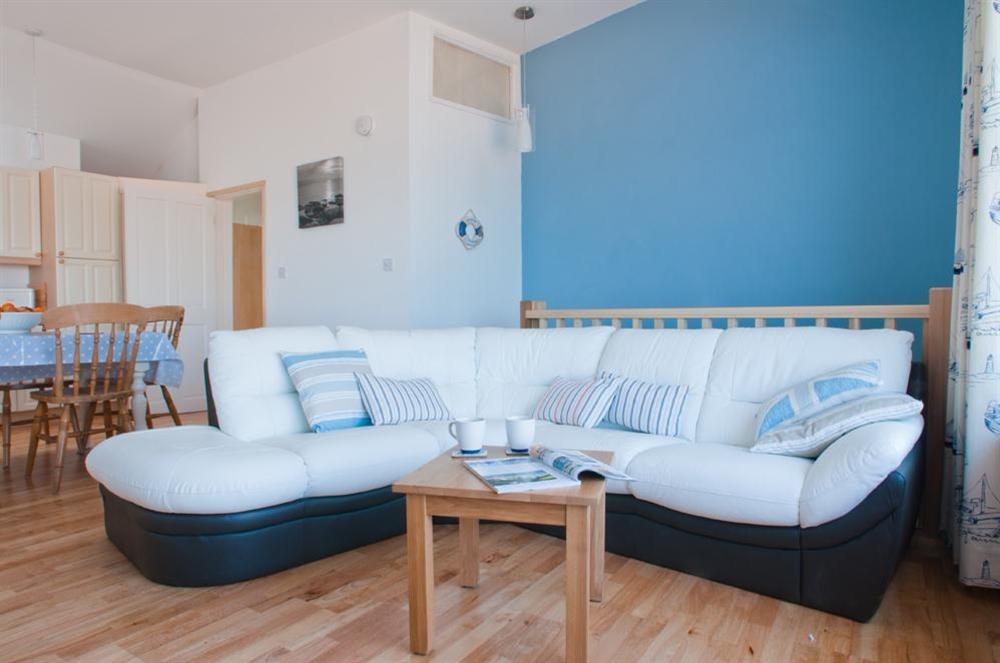 Lounge area with large white corner sofa at Boathouse Cottage in Torcross, Kingsbridge