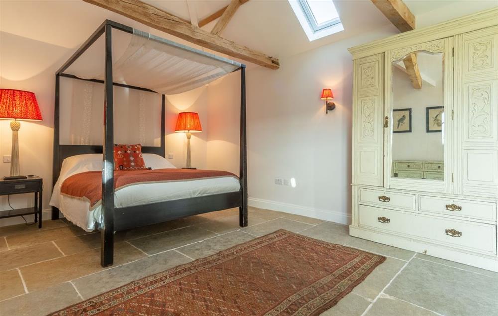Bedroom with 5’ king size four poster bed, seating area and archway through to the en-suite bathroom