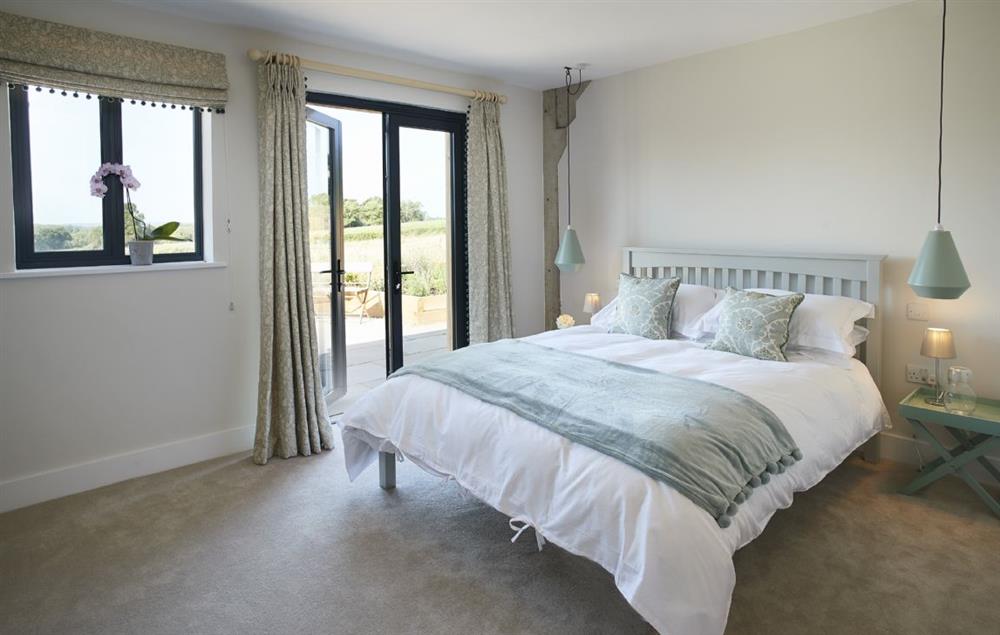 Bedroom one with a king-size bed and en-suite shower room.  French doors lead to the terrace at Bokes Barn, Hawkhurst