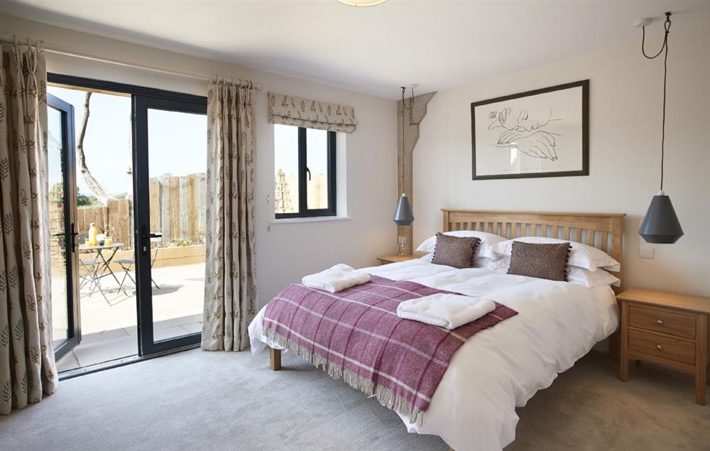Bedroom two with a king-size bed, en-suite shower room and french doors leading to the terrace at Bokes Barn, Hawkhurst